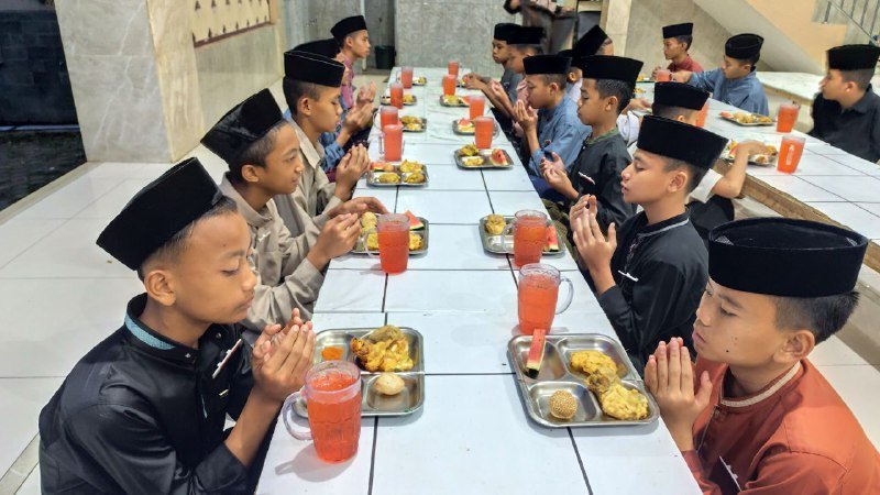 A group of children praying at a long table AI-generated content may be incorrect.